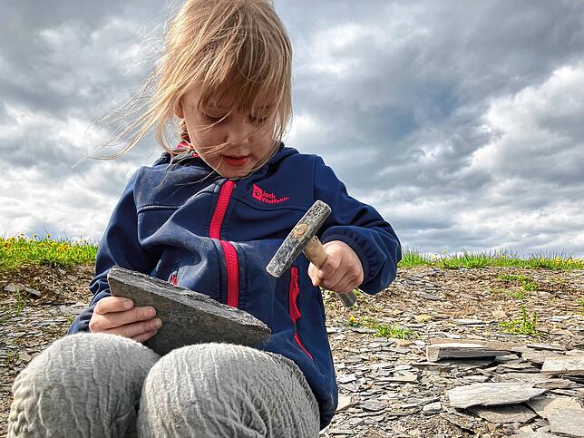 Die fünfjährige Henriette bearbeitet ein Stück Schiefer mit dem Hammer auf der Suche nach Fossilien. Das Bild wurde im Mai 2023 im ...