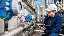 Ein E+H-Mitarbeiter prüft eine Messtechnikanlage bei einem Industriekunden. Foto: E+H