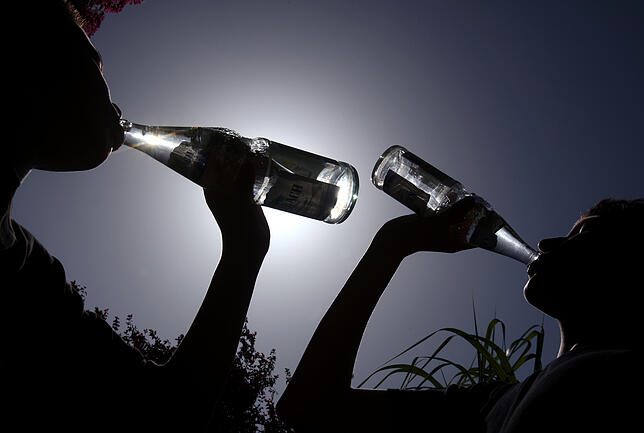 Mineralwasser trinken Mindestens zwei bis vier Liter Wasser oder Tee sollte man bei den hohen Temperaturen trinken. Und keinen Alkohol. Bild: dpa