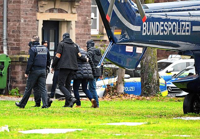 Eine Person (2.v.r.) wird nach den Razzien von Polizisten in Karlsruhe aus einem Hubschrauber gebracht.
