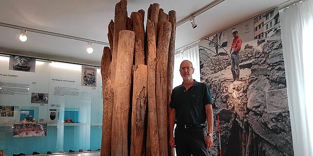 Ralph Röber im Konstanz-Raum neben typischen mittelalterlichen Holzständern, auf denen Teile der Stadt ruhen, wie auf dem Foto dahinter ...