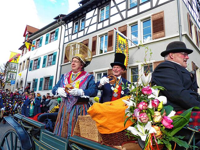 In der Chaise fahren die Narreneltern und werfen Brezeln aus.