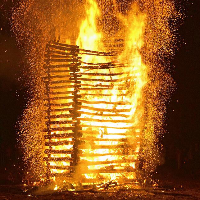 Es dauert über eine Stunde, bis der kunstgerecht aufgerichtete Stapel aus Baumstämmen, Christbäumen und Holzpaletten zusammensackt.