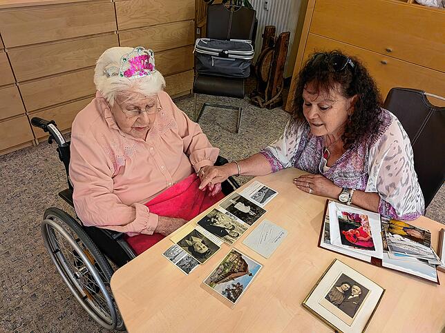 Melanie Moser (l.) und Pflegerin Kerstin Matejka schauen sich gemeinsam alte Fotos an.