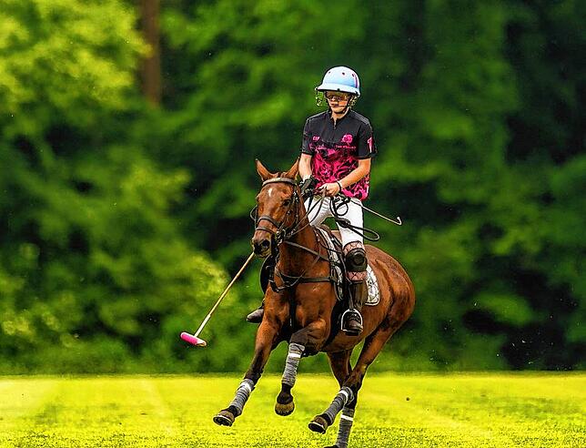 Christabel galoppiert über das Polofeld. Ihr Reithelm hat ein spezielles Gitter, das die Spieler vor dem harten Ball schützt.