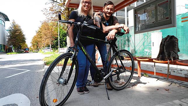 Kirsten Plischke und Dirk Volk vor einer Bushaltestelle im Konstanzer Industriegebiet. Dirk Volk hat das Fahrrad dabei, das er und seine ...