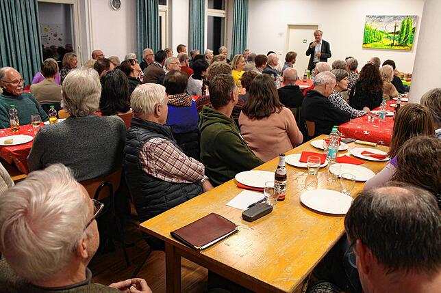 Autor Hubert Steinmann (hinten) stellt im vollen St. Oswaldsaal des Pallottiheims seine von ihm verfasste Hengelau-Chronik vor.