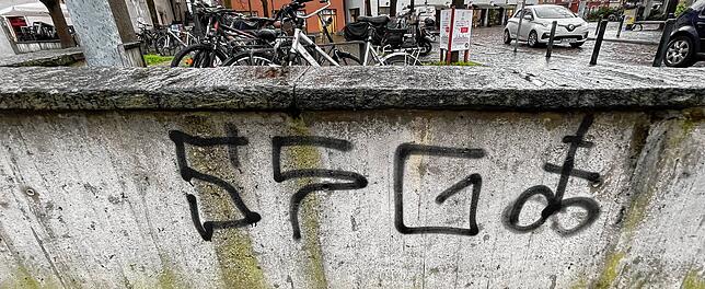 Auch auf dieser Mauer ist die Abkürzung samt Symbol zu sehen.