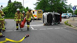 Feuerwehrleute beseitigen aus dem Unfallauto ausgetretenen Treibstoff.
