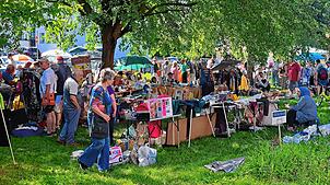 Besucher bummeln im Schatten von Bäumen zwischen den Ständen des SÜDKURIER-Flohmarkts umher.