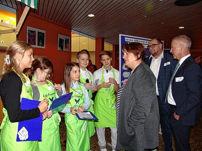 Die Mitglieder der Schülerfirma „Café Vogelnest“ nehmen die Getränkebestellungen entgegen. Kultusministerin Theresa Schopper erzählt in ...