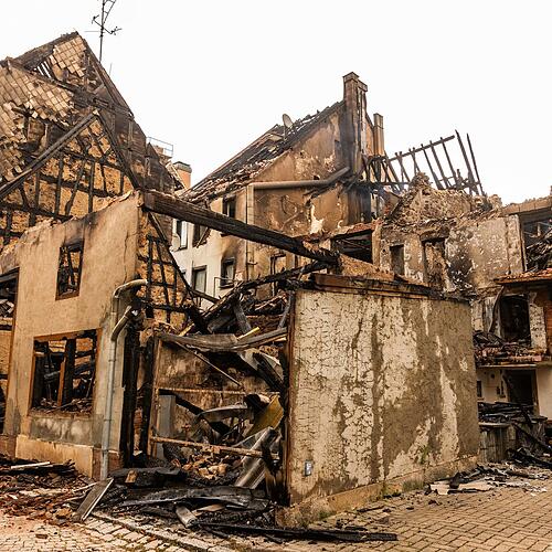16.06.2025, Baden-Württemberg, Villingen-Schwenningen: Schutt liegt zwischen den Mauerresten eines ausgebrannten Hauses. Am Vorabend ist ...