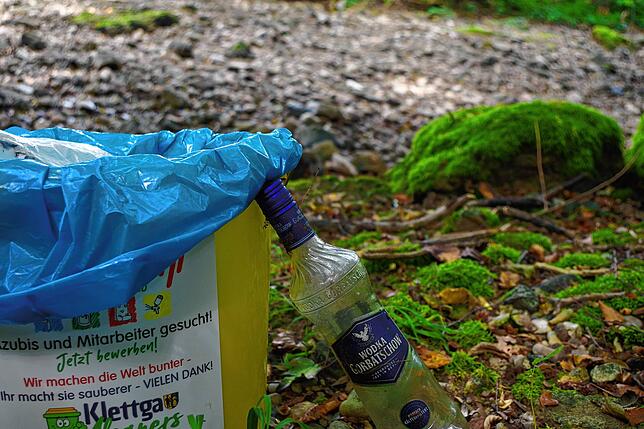 Eine leere Wodkaflasche steht neben einem Eimer der freiwilligen Müllsammler.