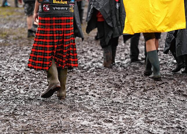 Metal-Fans gehen durch den Matsch auf dem Festivalgelände des Wacken Open Airs.