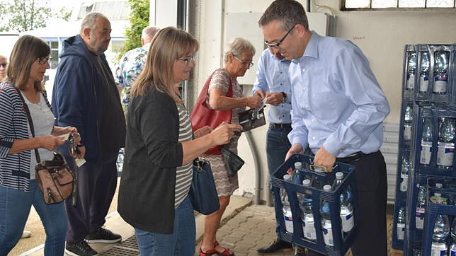 Martin Schwellinger, der Personalleiter der Stadtwerke, lässt sich von Bürgern den Ausweis zeigen und verteilt dann das Mineralwasser.