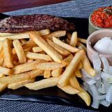 Pljeskavica, ein Hackfleischleib mit Käse gefüllt, dazu Pommes, Zwiebeln und Ajvar.