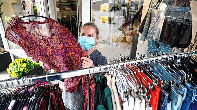 Verkäuferin Josi Mayer aus Friedrichsahfen trägt einen Mundschutz und kontrolliert vor der geöffneten Modeboutique Vis a Vis eine Bluse. ...