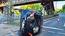 Nach der Kollision mit einer Ampel überschlägt sich ein mit drei Personen besetztes Auto und bleibt auf der Seite liegen.