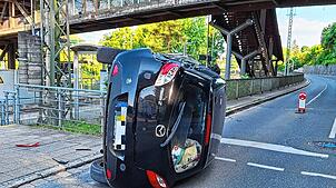 Nach der Kollision mit einer Ampel überschlägt sich ein mit drei Personen besetztes Auto und bleibt auf der Seite liegen.