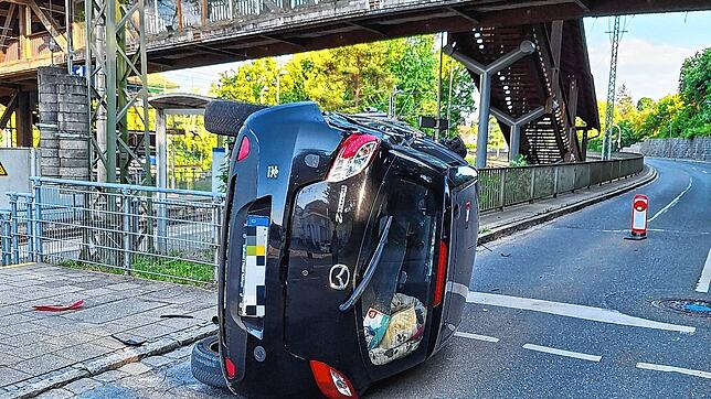 Nach der Kollision mit einer Ampel überschlägt sich ein mit drei Personen besetztes Auto und bleibt auf der Seite liegen.