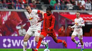 Leipzigs Lukas Klostermann (l) und Münchens Michael Olise kämpfen um den Ball. FC Bayern verpasst einen Sieg in Leipzig und vertagt ...