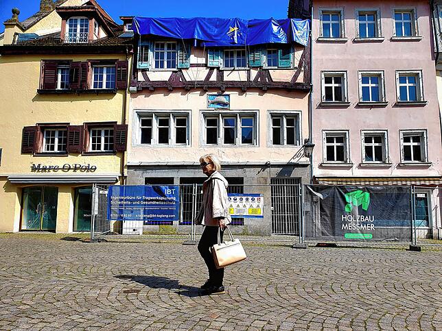 Eine Frau geht über die Hofstatt in Überlingen, ein Jahr nach dem Brand, bei dem im April 2023 ein Haus zerstört wurde.