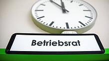 Eine Uhr an einer Info-Wand in einer Druckerei zeigt über einem Schild mit der Aufschrift &bdquo;Betriebsrat&ldquo;. Gerade beginnen in ...