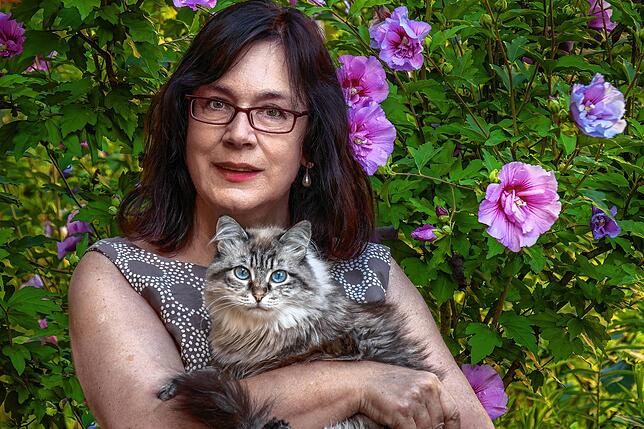 Marianne Kaindl mit ihrer Katze Mira im heimischen Garten. Momentan genießen sie die Ruhe. Es handelt sich um ein Selbstporträt.