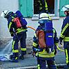 Ein Feuerwehrmann löscht den noch glimmenden Grill, der möglicherweise den Brand verursacht hat.