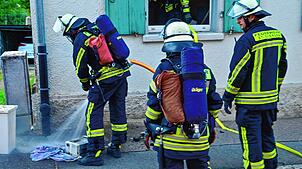 Ein Feuerwehrmann löscht den noch glimmenden Grill, der möglicherweise den Brand verursacht hat.