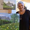Die Malerin Rita Leber in ihrer Ausstellung im Stadtmuseum neben der Staffelei mit Südtiroler Landschaften.