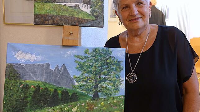 Die Malerin Rita Leber in ihrer Ausstellung im Stadtmuseum neben der Staffelei mit Südtiroler Landschaften.