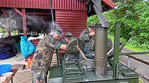 Die Feldköche, beim großen Löffel Peter Haug, bei der Arbeit an der originalen Armee-Feldküche, in der die Erbsensuppe gekocht wird.