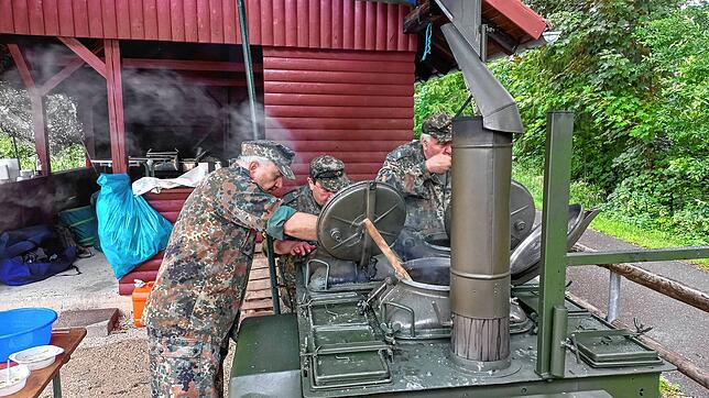Die Feldköche, beim großen Löffel Peter Haug, bei der Arbeit an der originalen Armee-Feldküche, in der die Erbsensuppe gekocht wird.