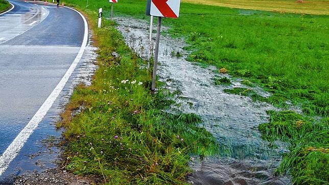 Das Wasser zieht sich bei Aasen wieder zurück. Nach einem heftigen Starkregen war die Straße überspült. Die Feuerwehr sichert den Bereich.