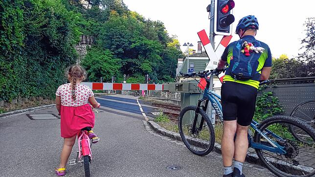 Auch Radfahrer und Fußgänger stehen vor der geschlossenen Schranke.