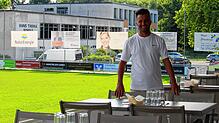 Dennis Carmelini (38) an seinem Arbeitsplatz, der &bdquo;Restobar&ldquo; in Warmbach. Im Hintergrund seine ehemalige Schule.