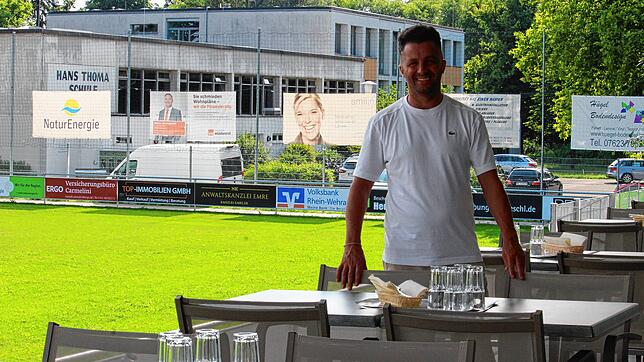 Dennis Carmelini (38) an seinem Arbeitsplatz, der &bdquo;Restobar&ldquo; in Warmbach. Im Hintergrund seine ehemalige Schule.