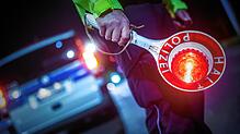 Ein Polizeibeamter hält eine Kelle zum Stoppen des Verkehrs in der Hand (Symbolbild). Doch ein 22-Jähriger ließ sich weder von Kelle ...