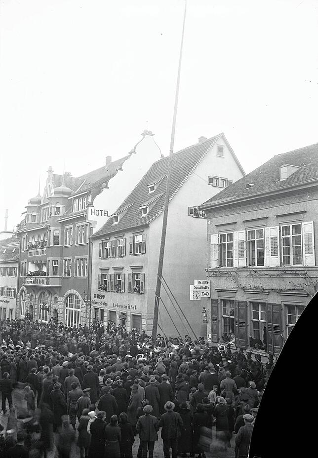 Narrenbaumsetzen am Lebensmittel-Geschäft G. Stocker und Friseur-Salon H. Hepp am 16.02.1939. Glasplatten-Negativ mit Schaden rechts unten.