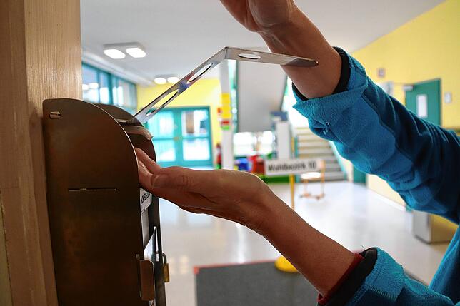 Eine Frau desinfiziert vor dem Wahllokal des Bezirks 10 ihre Hände: Diese OB-Wahl ist die erste unter Corona-Bedingungen. Wählende ...