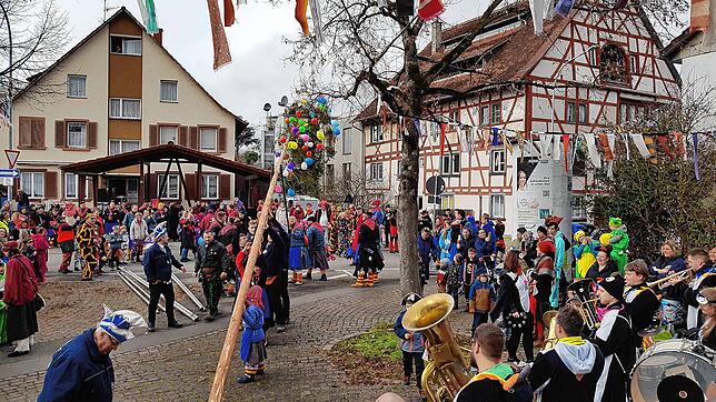 Das war gar nicht so einfach: Es dauerte eine Weile, bis der Narrenbaum in Wollmatingen stand. Die Vollharmonie rechts im Bild spielte ...