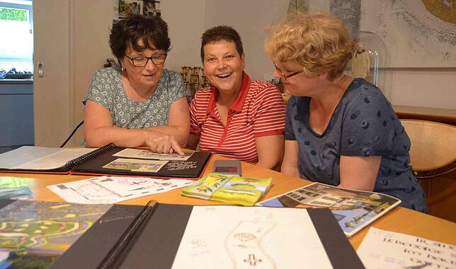 Brigitte Bauder (von links), Inge Steffelin und Silvia Pfriender beim Betrachten von Blumenteppich-Bildern der vergangenen Jahre.