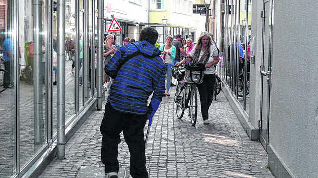 Ein Bettler humpelt auf Krücken durch die Konstanzer Altstadt