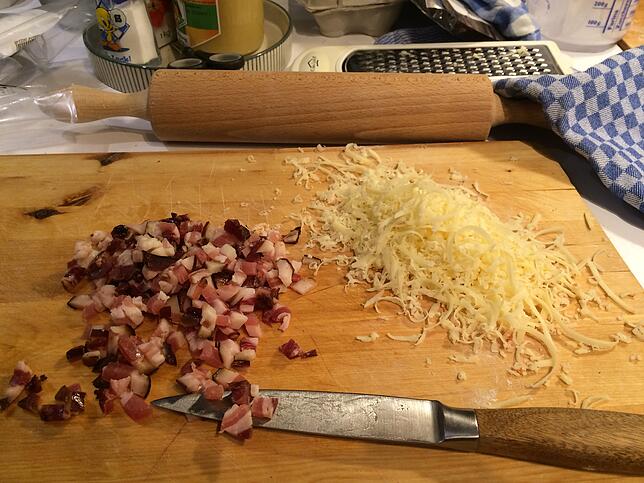 Für die Sauce werden regionaler Speck gewürfelt und Hartkäse gerieben.