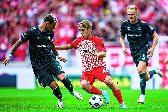 Freiburgs Ritsu Doan (M) in Aktion gegen Bremens Marco Friedl (l) und Bremens Amos Pieper (r).