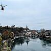 Ein Helikopter transportiert ein Pylon für die Laufenburger Acht an, das Arbeiter zwischen Bahnlinie und Rheinufer verankern.