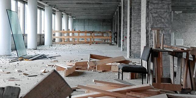 Überbleibsel nach Jahrzehnten als Büroturm: Ein Stuhl und Rohmaterial. Hinten beim Bretterzaun ist ein Durchbruch ins nächste Stockwerk ...