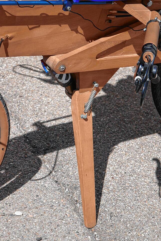 Das gut 20 Kilogramm schwere Holzliegefahrrad kann auf einem hölzernen Seitenständer abgestellt werden.