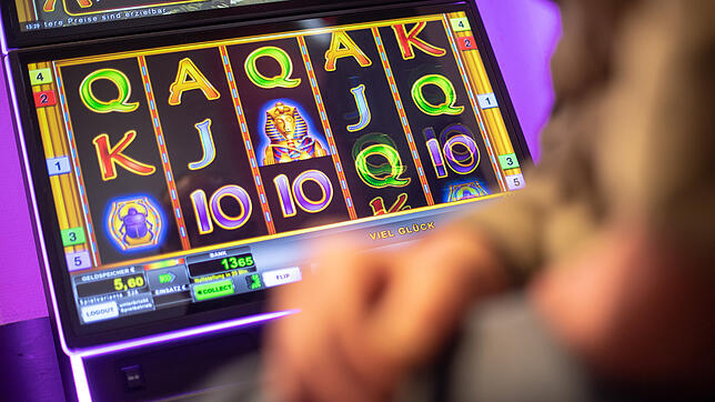 Ein Mann sitzt an einem Spielautomaten. Zu den Gewinnern gehören der Betreiber des Geräts und die Gemeinde &ndash; wenn sie denn ...